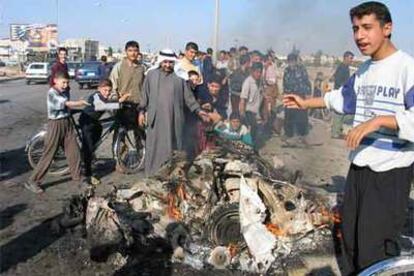 La multitud se agolpa en torno a los restos de un coche bomba que ha explotaso cerca de un convoy de seguridad en Mosul.