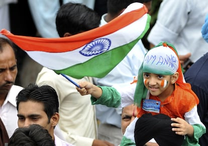 Un joven simpatizante sentado sobre los hombres de su padre sostiene la bandera nacional india por fuera de la prisión. La policía llegó a un acuerdo con el activista anticorrupción: Hazare puede salir a la cárcel pero debe limitar su ayuno en 15 días y no "hasta la muerte", como pretendía. Su demanda es que se revise la propuesta de ley contra la corrupción y que el primer ministro y otros cargos públicos puedan ser sometidos a investigación, algo que el proyecto presentado excluye.