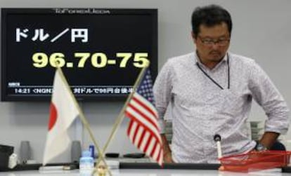 Un empleado de una oficina de corretaje frente a una pantalla con la cotización del dólar respecto al yen, en Tokio.