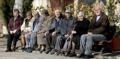 Varios ancianos toman el sol en unos bancos de Olmeda de la Cuesta, Cuenca. 