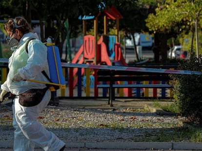 Una trabajadora municipal desinfecta las proximidades un parque infantil clausurado en la localidad madrileña de Alcobendas.