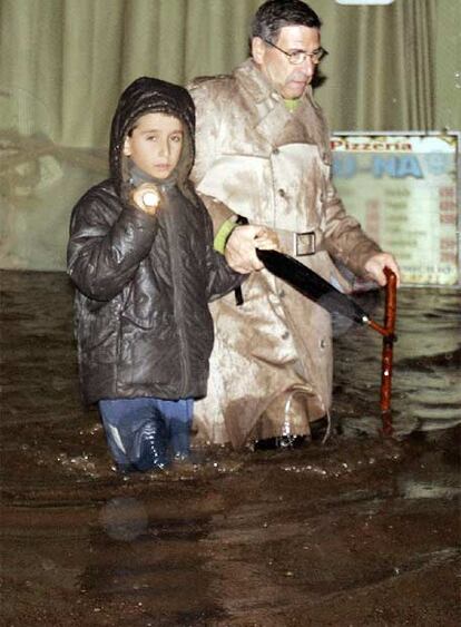 Dos vecinos de Vilagarcía de Arousa intentan cruzar la calle inundada.