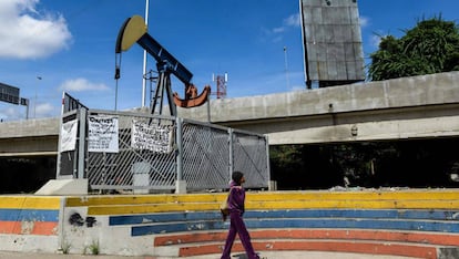 Mulher caminha diante de uma bomba de extração de petróleo na Universidade de Caracas