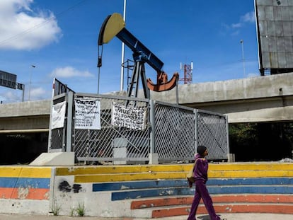 Mulher caminha diante de uma bomba de extração de petróleo na Universidade de Caracas