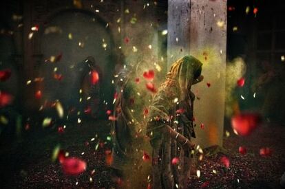 Una mujer baila bajo los pétalos y los polvos de colores del Holi.