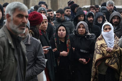 People wait as rescue operations take place on a site after an earthquake in Diyarbakir.