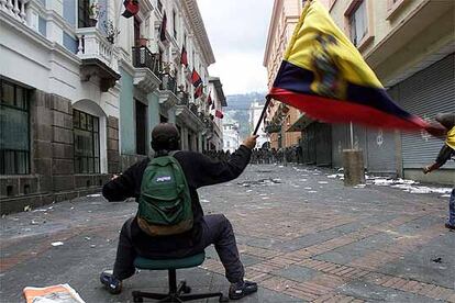 La presión de la ciudadanía ecuatoriana, que se había echado a la calle días atrás para protestar por el gobierno del presidente Lucio Gutiérrez, consiguió su objetivo. Un protestante blande una bandera de Ecuadors frente a la policía mientras custodiaba el palacio presidencial en las revueltas de ayer.