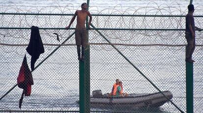 Un migrante se agarra a la valla de Ceuta durante un salto, el pasado mes de agosto.