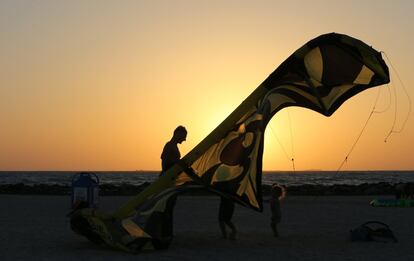 Un hombre y sus hijos preparan la vela de su kitesurf en Kite Beach en Dubái, Emiratos Árabes Unidos.