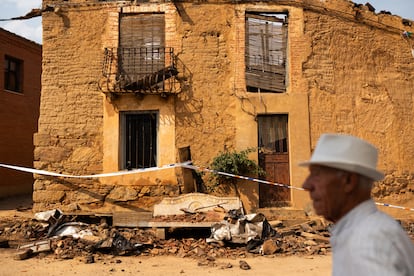 Una persona pasa delante de una casa afectada por el fuego, este jueves, en Carracedo de Vidriales (Zamora).