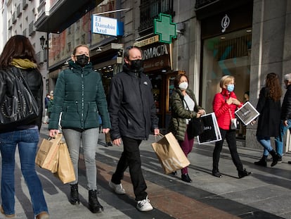 Varias personas con bolsas pasean en una calle comercial del centro de Madrid, (España).