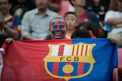 Un aficionado del Barcelona sostiene una bandera del equipo catalán en el estadio Rajamangala de Bangkok. 