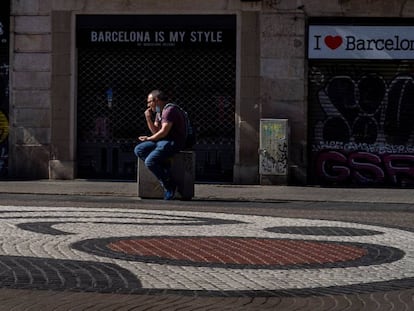 Un home a la Rambla davant de botigues per a turistes.