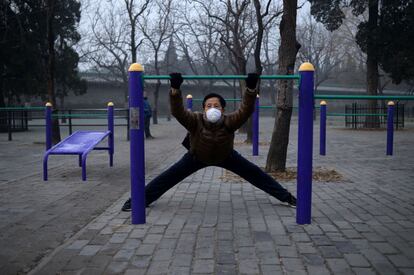 Un hombre con mascarilla realiza ejercicios en un parque de Pekín (China).