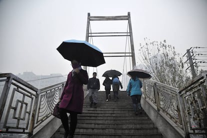 Algunas personas pasan delante de un edificio envuelto en una severa contaminaci&oacute;n del aire en Harbin, China.