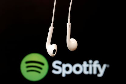 Auriculares en primer plano sobre el logotipo de Spotify. 