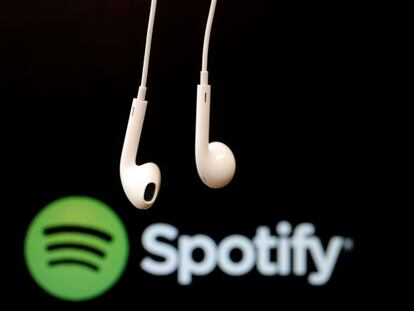 Auriculares en primer plano sobre el logotipo de Spotify. 