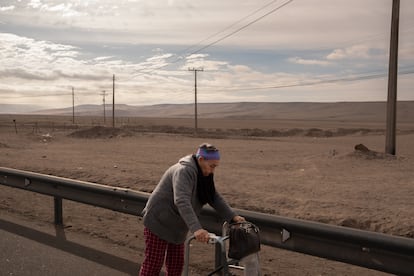 Una mujer venezolana de la tercera edad camina sobre una carretera junto al cruce fronterizo entre Chile y Perú.