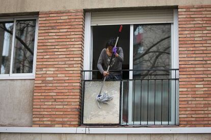 Una dona neteja l'exterior del seu balcó.