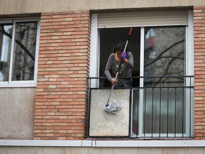 Una dona neteja l'exterior del seu balcó.