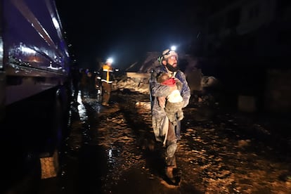 A member of the Syrian civil defence, known as the White Helmets, carries a child rescued from the rubble following an earthquake in the town of Zardana in the countryside of the northwestern Syrian Idlib province.