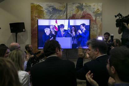 Seguidores de Junts per Cataluña siguen la intervención de Carles Puidemont por videoconferencia en Barcelona.