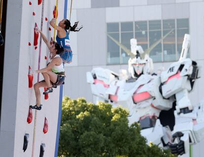 La japonesa Akiyo Noguchi (arriba) y la eslovena Mia Krampl compiten en escalada frente al robot xe la animación japonesa 'Unicorn Gandam' de fondo.