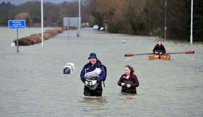 Unas personas tratan de cruzar una carretera inundada cerca de Egham, al oeste de Londres, el 12 de febrero de 2014. 