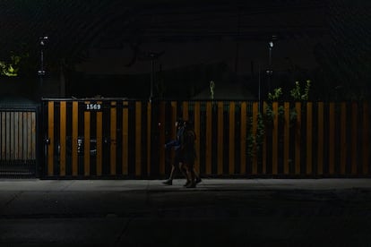 Transentes caminan por las calles de Santiago iluminadas solo por las luces de los autos, este martes.