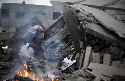 Ciudadanos palestinos entre los escombros del edificio del Gobierno de Gaza destruido durante la madrugada del sábado por bombas israelíes.