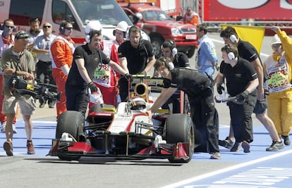 El piloto español Dani Clos es llevado por sus mecánicos al 'box' de HRT.