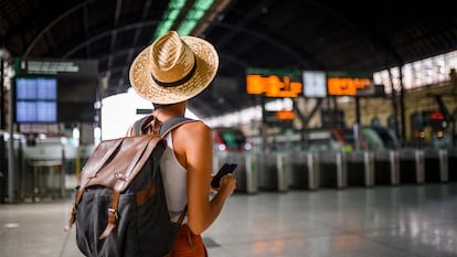 Una chica de espaldas en la estación de tren con su mochila.