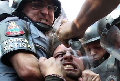 Policial dispara spray de pimenta em manifestante imobilizado.