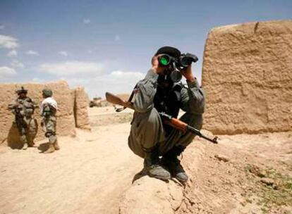 Un soldado afgano observa con unos prismáticos durante una patrulla con soldados estadounidenses (al fondo) en Maquor, provincia de Paktia.