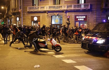 Un manifestante empuja una moto hacia un vehículo de los Mossos, este miércoles en Barcelona.
