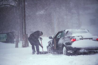 Homem tira neve das rodas de seu veículo em Bellport, no Estado de Nova York.