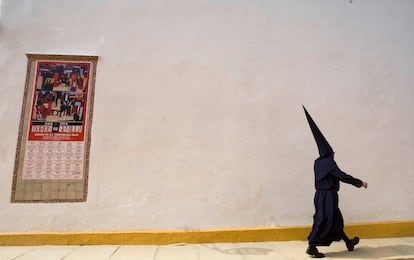 Un nazareno de la hermandad sevillana del Baratillo pasa camino de la iglesia junto a la Real Maestranza de Caballería.