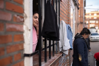 Una mujer se asoma a la ventana de una de las viviendas del barrio.