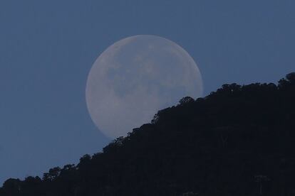 Lla Luna llena se esconde tras las montañas, durante el amanecer en Medellín (Colombia).