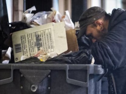 Dos personas buscan comida en una calle de Barcelona.