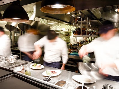 Varios cocineros trabajan en el interior de una cocina profesional.