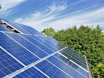 Un operario instala paneles solares en el tejado de una casa.