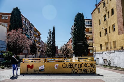 Un hombre mira su móvil junto a una pintada contra los turistas en el distrito de Puente de Vallecas.