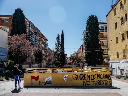 Un hombre mira su móvil junto a una pintada contra los turistas en el distrito de Puente de Vallecas.