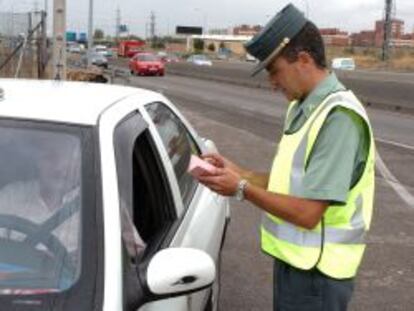 Un agente de la Guardia Civil mira la documentaci&oacute;n de un conductor.