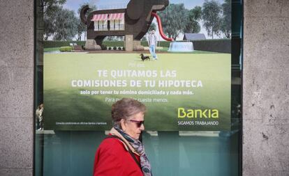 Una mujer pasa ante cartel que publicita hipotecas en una sucursal bancaria.