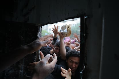 Palestinos desplazados se asoman a la ventana de una panadería para intentar conseguir pan en el campo de refugiados de Nuseirat, este jueves en la Franja.