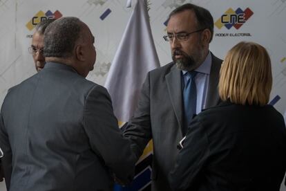 El presidente del Consejo Nacional Electoral (CNE) de Venezuela, Elvis Amoroso (i), estrecha la mano del presidente de la Comisión Nacional de Primarias, Jesús María Casal (c), tras ofrecer una rueda de prensa, en Caracas.