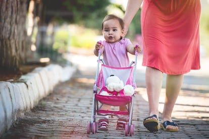 Una niña pasea con un carrito de juguete.