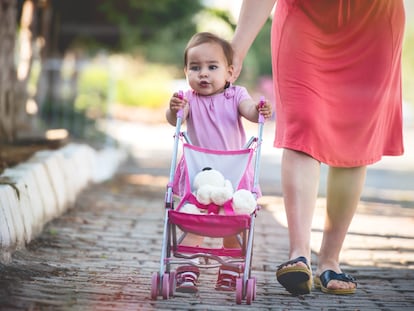 Una niña pasea con un carrito de juguete.